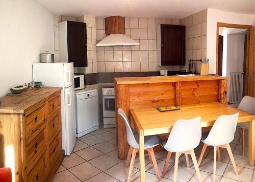 une cuisine avec une table en bois et des appareils électroménagers blancs dans l'établissement Appartement GENEPI 1350, à Saint-Chaffrey