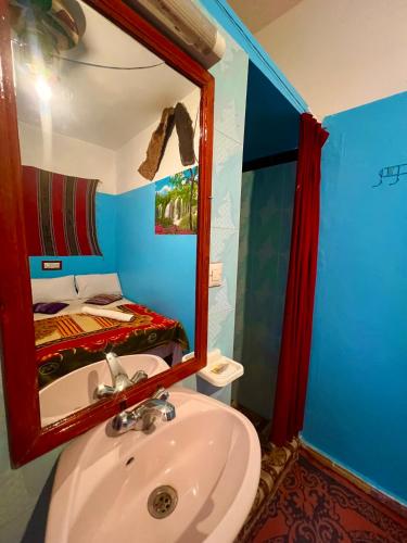 a bathroom with a sink and a mirror and a bed at Maison d'hôte Riad Todra in Tinerhir
