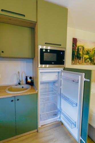 a kitchen with an open refrigerator with a microwave at Breeze Studios Saturn in Saturn