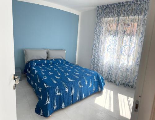 a bedroom with a bed with a blue comforter and a window at Bilocale completamente rinnovato a 100 metri dal mare con giardino in Marina di Massa