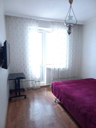 a bedroom with a bed and a table and a window at Apartment On Pribuzhskaya 2 in Khmelʼnytsʼkyy