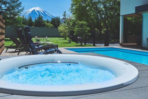 a hot tub in front of a pool with a mountain at Villa Saison Fuji ヴィラ セゾン フジ in Fujikawaguchiko