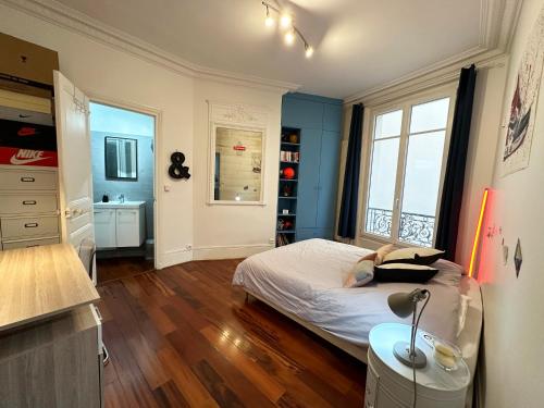 une chambre avec un lit aux murs bleus et une fenêtre dans l'établissement Appartement spacieux Arc de Triomphe Paris, à Paris