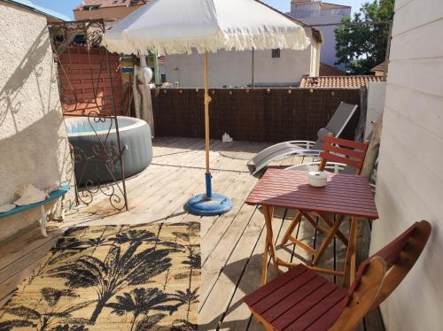un patio avec un parasol, une table et des chaises dans l'établissement Chambre cabane de charme, terrasse et spa privé, à Valras-Plage