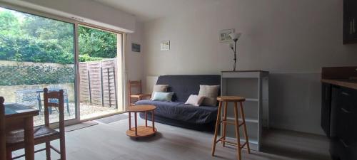 - un salon avec un canapé et deux tabourets de bar dans l'établissement Appartement 2 pièces de plein pied au coeur du village a deux pas de la plage avec extérieur et parking prive, à Saint-Georges-de-Didonne