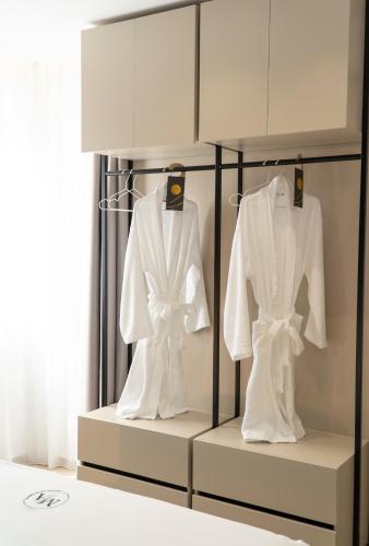 two white shirts on hangers in a room at Mateo Apartments in Sarandë
