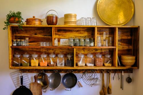 a shelf with jars and utensils on a wall at The Jungalow by AVVAs Stays in Bīr