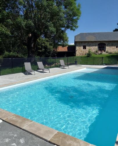 une piscine bleue avec deux chaises et un bâtiment dans l'établissement Sous Le Tilleul, à Sénaillac-Latronquière