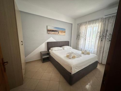 a bedroom with a bed with white sheets and a window at Skenderi Apartments in Ksamil