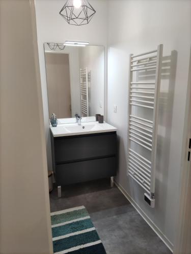 une salle de bain avec un lavabo et un miroir dans l'établissement La Nouvelle Vague, à Carcans