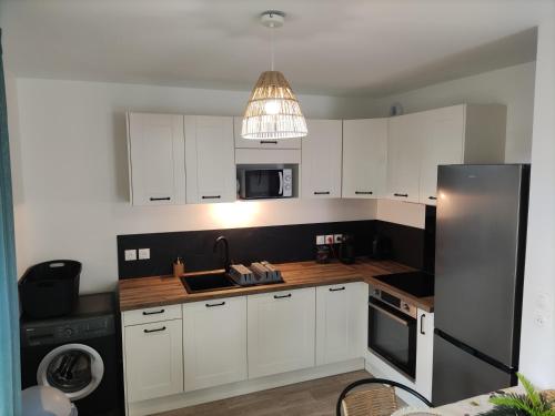 eine Küche mit weißen Schränken und einem silbernen Kühlschrank in der Unterkunft La Nouvelle Vague in Carcans