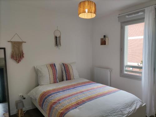 ein Schlafzimmer mit einem Bett mit einer bunten Decke darauf in der Unterkunft La Nouvelle Vague in Carcans