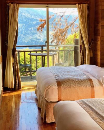 two beds in a room with a large window at The Cotswolds Villa in Renai