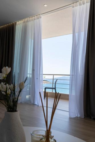 a vase with flowers on a table in front of a window at Mateo Apartments in Sarandë