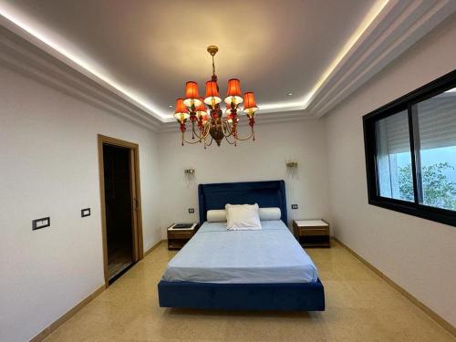 a bedroom with a blue bed and a chandelier at Villa gammarth avec piscine in Gammarth