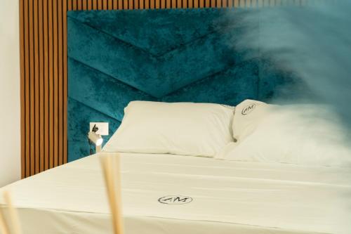 a bed with white pillows and a blue wall at Mateo Apartments in Sarandë