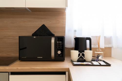 a microwave sitting on a counter with two coffee cups at Mateo Apartments in Sarandë