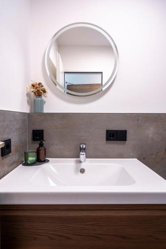 a bathroom with a white sink and a mirror at Suite Apartment modern getaway - Neu renoviert - Strobl am Wolfgangsee in Strobl