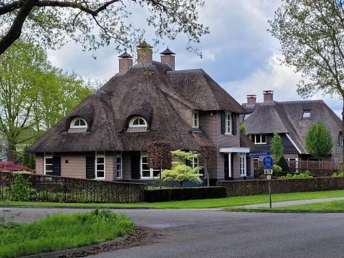 a house with a thatched roof on a street at Villa in Overloon near War Museum and Zoo in Overloon