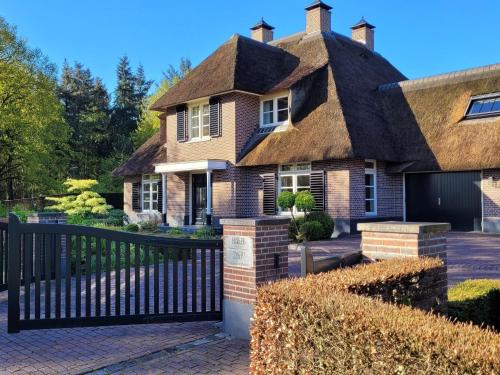 a thatched roof house with a black fence at Villa in Overloon near War Museum and Zoo in Overloon