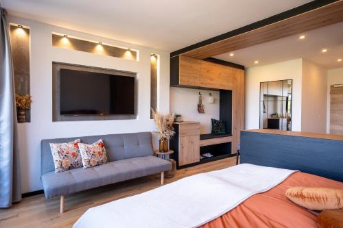 a bedroom with a bed and a couch and a tv at Suite Apartment modern getaway - Neu renoviert - Strobl am Wolfgangsee in Strobl