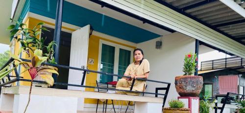 a woman sitting on the front porch of a house at Panutsaya Homestay in Wang Nam Khieo
