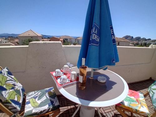 un parapluie bleu assis au-dessus d'une table dans l'établissement Charmante chambre avec vue mer - parking privée, à La Ciotat