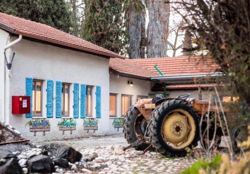a tractor parked in front of a house with blue shutters at אתרי קמפינג in Modi'in