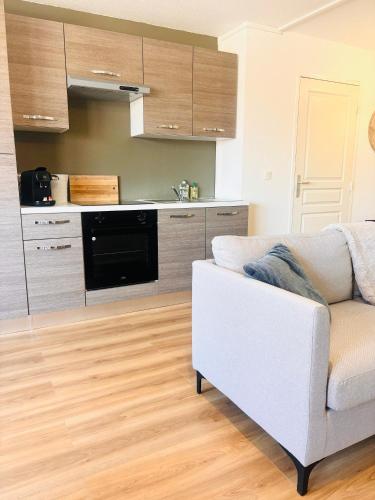 un salon avec un canapé blanc et une cuisine dans l'établissement Le Studio de Jeanne, à Mont-de-Marsan