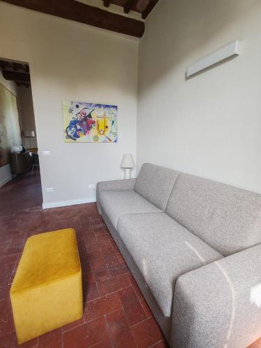 a living room with a gray couch and a yellow stool at L'Appartamento di Jò in Lucca