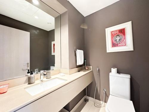 a bathroom with a sink and a mirror and a toilet at 3BR Modern Getaway in Yas Island with Gym&Pool 609WE in Abu Dhabi