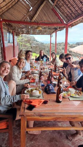a group of people sitting around a long wooden table at Nosy-Borah Holidays in Analabe