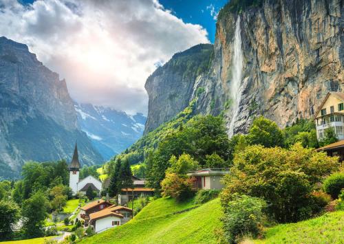 a village in the mountains with a waterfall at The Bluemlisalp, a private holiday flat with the lake of Thun view in Oberhofen am Thunersee