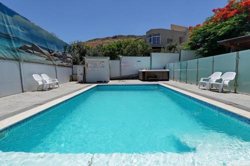 a swimming pool with two chairs next to a fence at שלווה במושבה מגדל - וילה מדהימה עם בריכה פרטית וג'קוזי ליד הכנרת in Migdal
