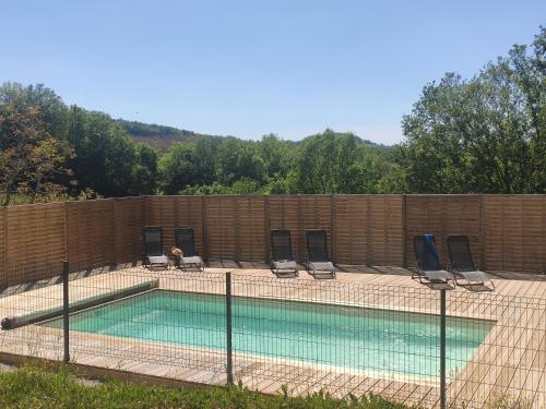 une piscine avec des chaises et une clôture dans l'établissement Les roulottes de Joséphine, à Veyrines-de-Domme