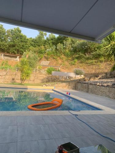 a swimming pool with an orange kayak in it at Paraiso Relax no Douro in São Cristóvão da Nogueira