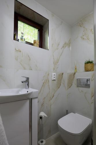 a white bathroom with a toilet and a sink at Chalet Senec in Senec
