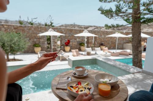 a person sitting at a table with a bowl of food at Oliving Mykonos Luxury Suites in Klouvas