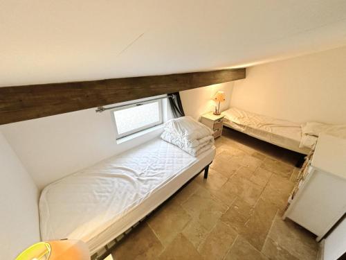 une petite chambre avec deux lits et une fenêtre dans l'établissement maison à la campagne, à Moulès