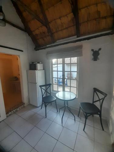 eine Küche mit Tisch und Stühlen und einem Kühlschrank in der Unterkunft Rosewood Cottage Apartment in Himeville