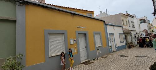 two girls standing next to a building on a street at La petite maison in Portimão