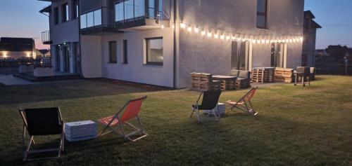 a group of chairs sitting in the grass in front of a house at Bursztynowa Rosa & Wypożyczalnia rowerów elektrycznych in Łeba