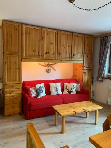 a red couch in a living room with wooden cabinets at Casa Bambi in Sella Nevea