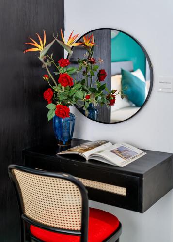 a mirror above a desk with a vase of flowers at Otis Soho Saigon Balcony Apartment in Ho Chi Minh City