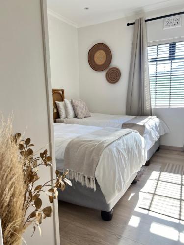 Un dormitorio con dos camas y una ventana. en Sage Serenity Retreat, en Ciudad del Cabo