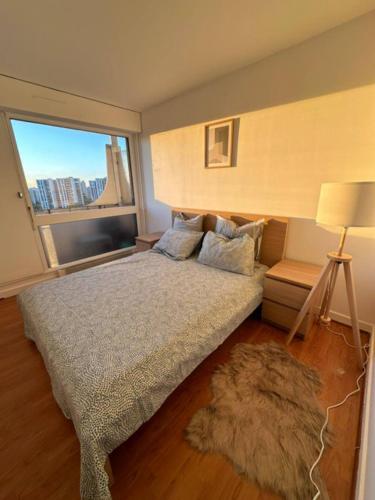 une chambre avec un grand lit et une grande fenêtre dans l'établissement Joli appartement vue tour Eiffel de loin, à Créteil