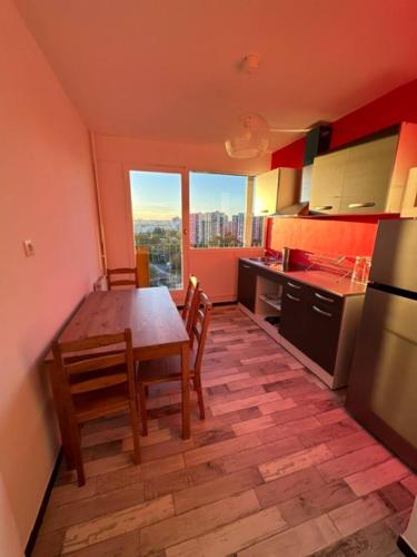 une cuisine avec une table et des chaises ainsi qu'une grande fenêtre dans l'établissement Joli appartement vue tour Eiffel de loin, à Créteil