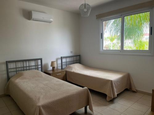 two beds in a room with a window at Hana Nissi in Ayia Napa