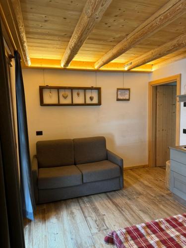 a couch in a living room with a wooden ceiling at Appartamenti al Ciariè in Cima Gogna