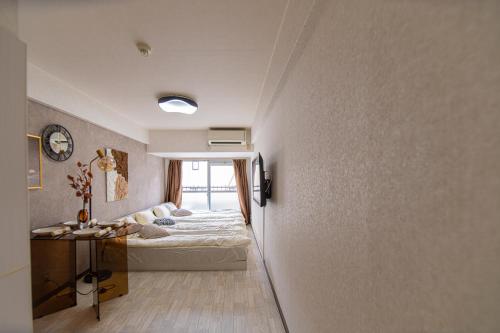 a bedroom with a bed and a clock on the wall at G57新宿最中心 東新宿站5分-Shinjuku center 5 mins to Station, Max 4 直达新宿 涉谷 表参道 池袋 上野 代代木 银座 原宿 in Tokyo